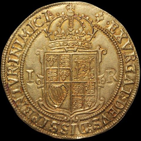 Colour photograph. Documentation of a shiny gold coin. The coin features text encircling its circumference, and has the royal British insignia, topped with a crown, embossed into the centre.