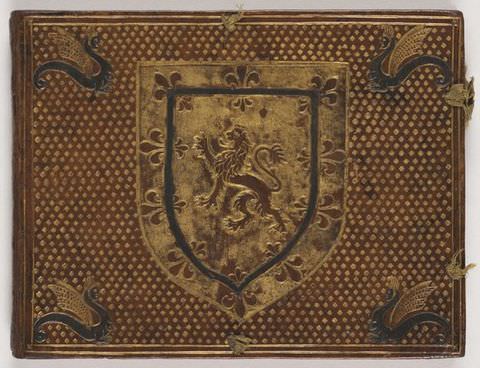 Colour photograph. The front cover of a decorated leather book in landscape format is seen face on. In the centre of the design is a herald shield featuring the English lion. In each of the four corners is a dragon seen side on, while the rest of the cover is adorned with a small diamond print.