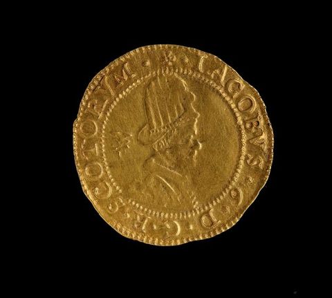 Colour photograph. A circular golden coin documented against a black backdrop. The coin features the portrait of a young man wearing armour and a crown, with a sword leaning on one shoulder, and a plant cutting in the other hand. A passage of text encircles the circumference of the coin.
