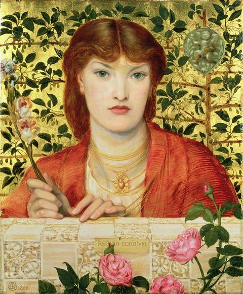 Painting. A colourful painting of a young woman from head to shoulder facing towards us. She has dark ginger hair, wears orange clothing, and a stacked series of gold necklaces. In one hand she carries a long stem with flowers. Before her is a strip of tiled wall, and roses grow in front. Behind her is an intricate leafy green pattern against a gold backdrop.